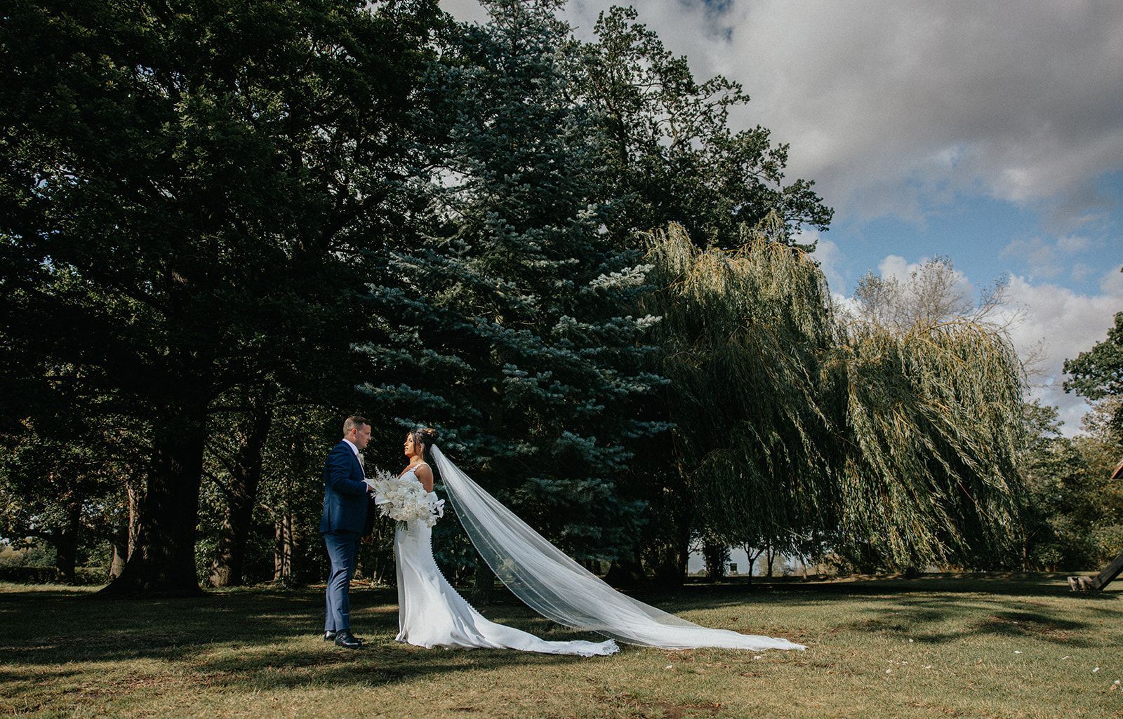 A bride and groom are standing next to each other on a path.