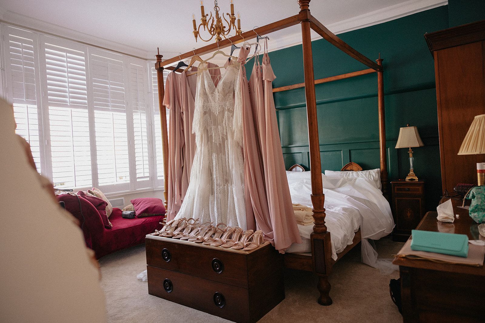 A wedding dress is hanging on a canopy bed in a bedroom.