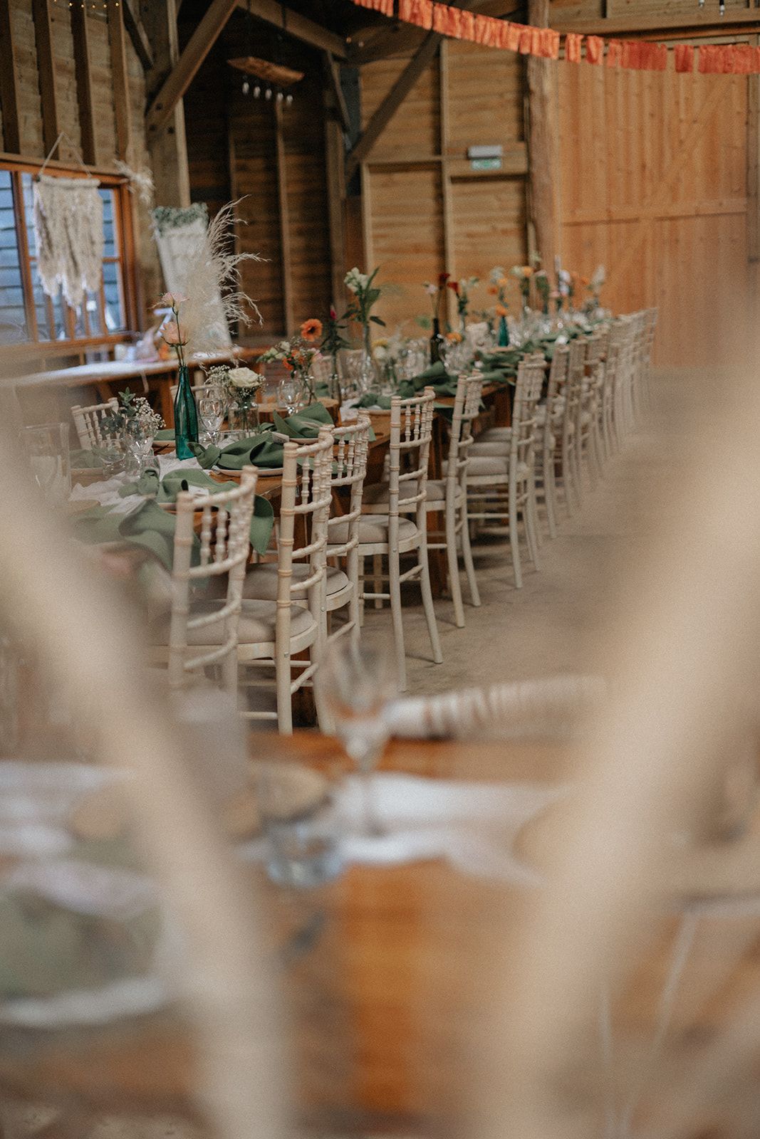 A long table with chairs and plates set up for a wedding reception.