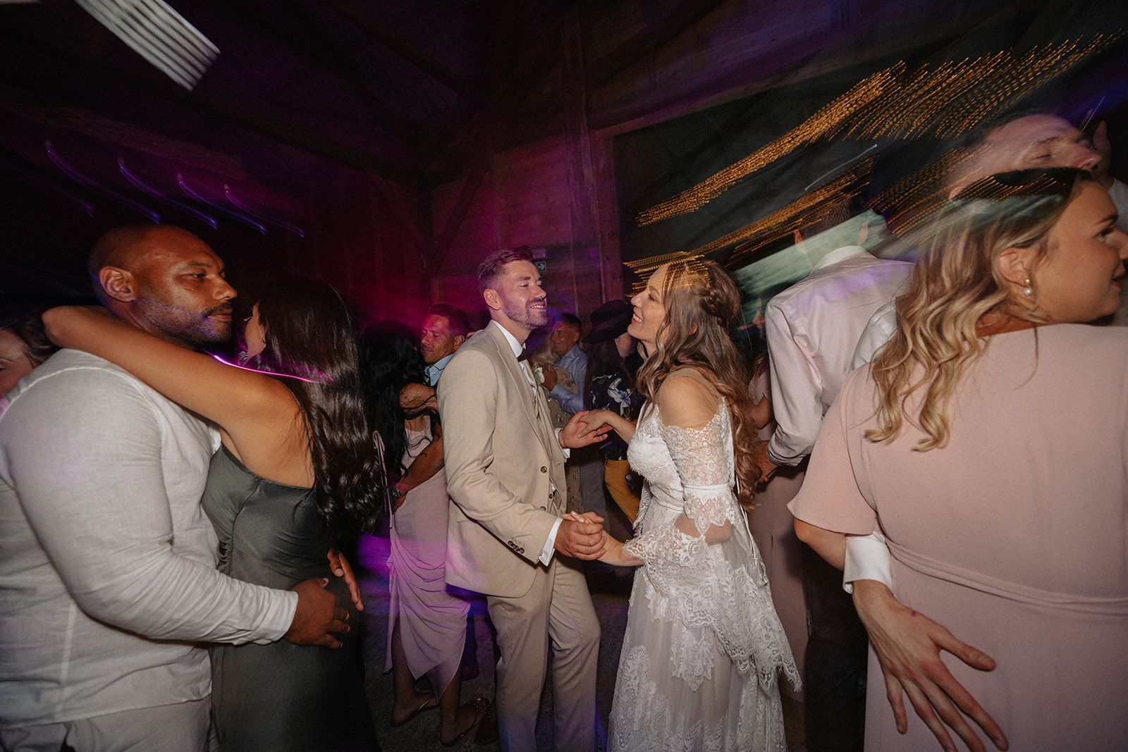 A bride and groom are dancing with their wedding guests at a wedding reception.