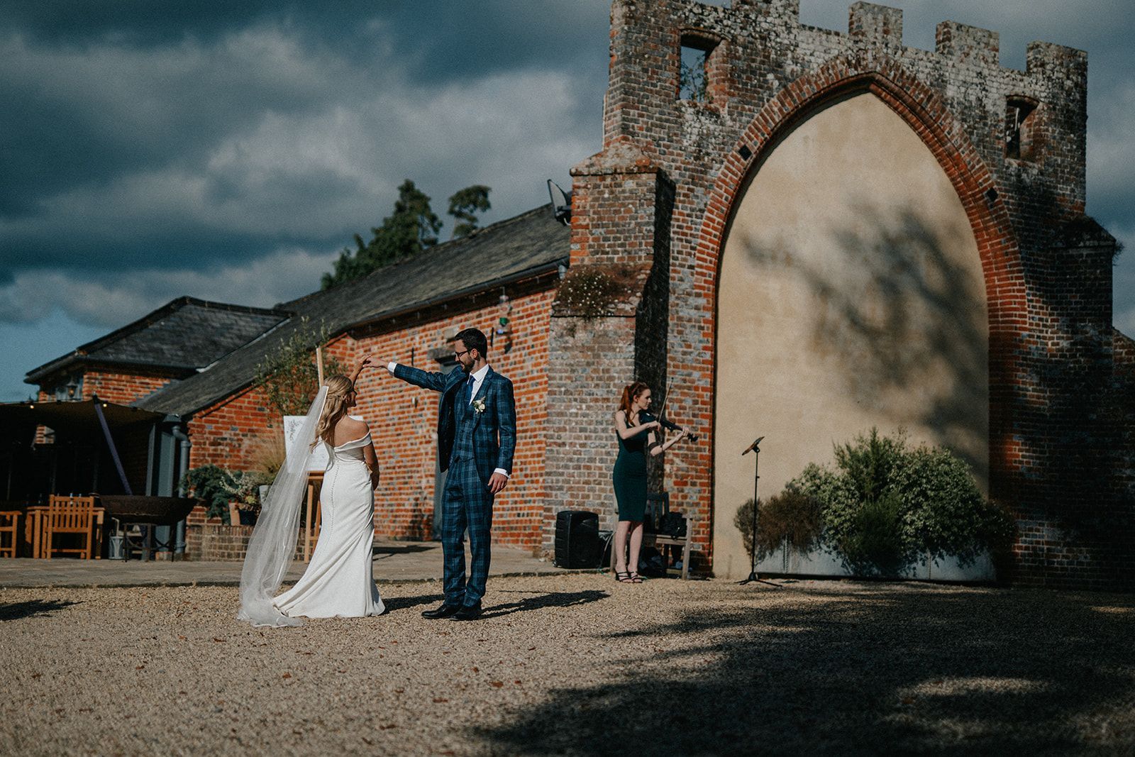 A bride and groom are dancing in front of a brick building.
