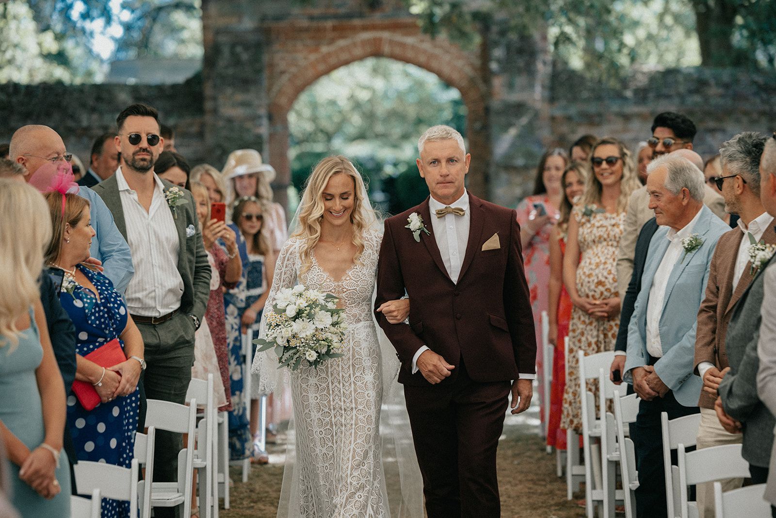 A bride and her father are walking down the aisle at a wedding.