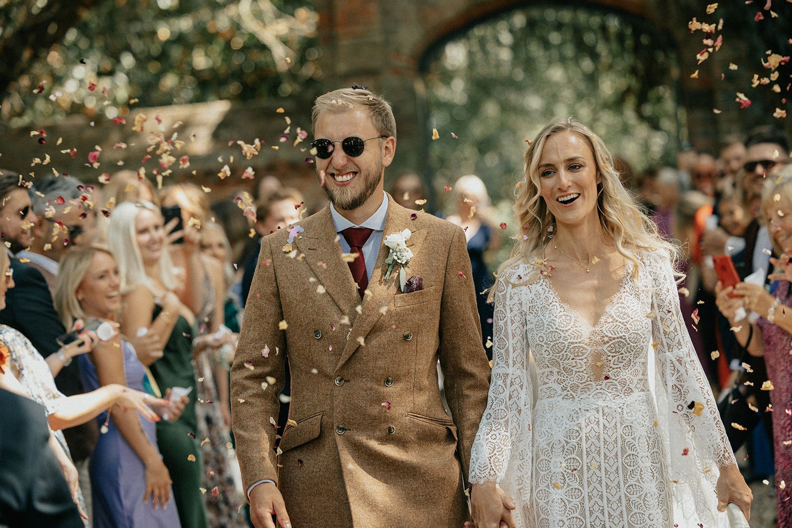 A bride and groom are walking down a aisle surrounded by confetti.