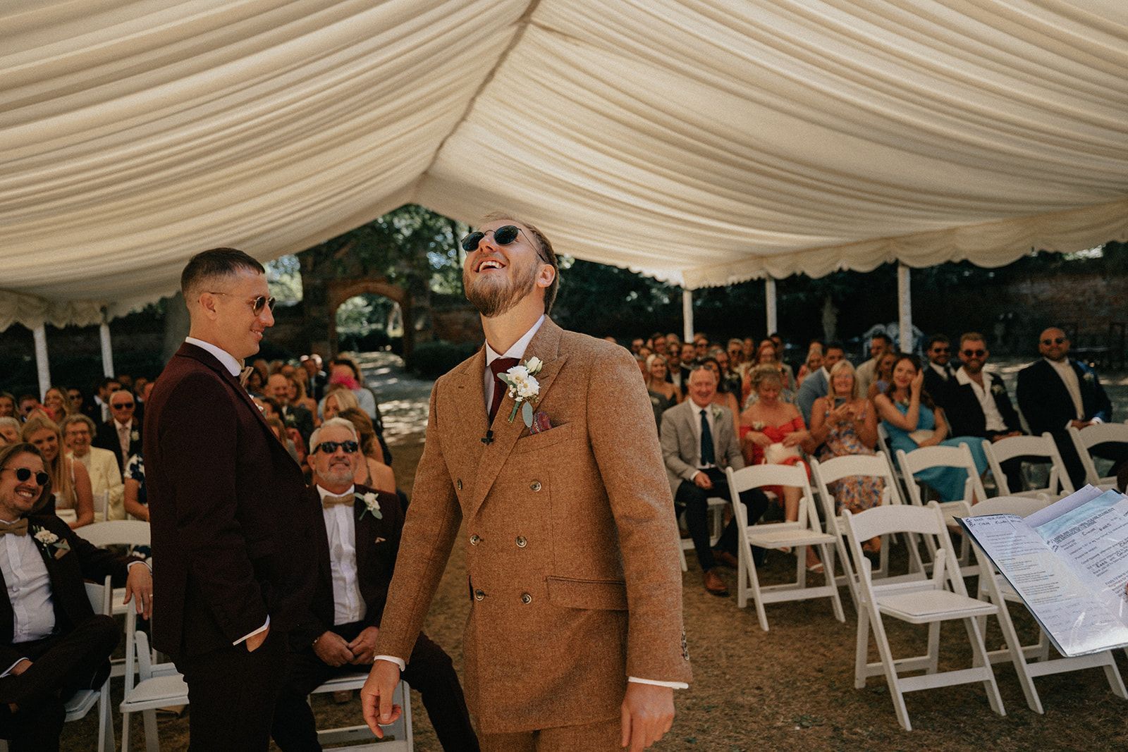 A bride and groom are walking down the aisle at their wedding under a tent.
