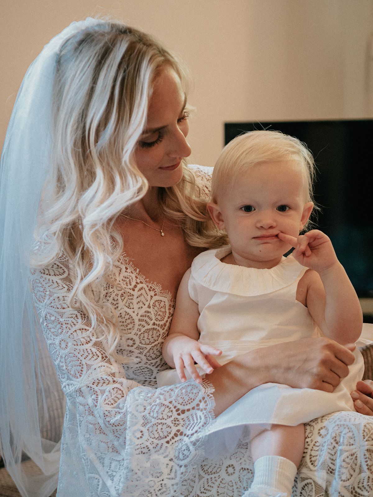 A woman in a white dress is holding a little girl in her arms.