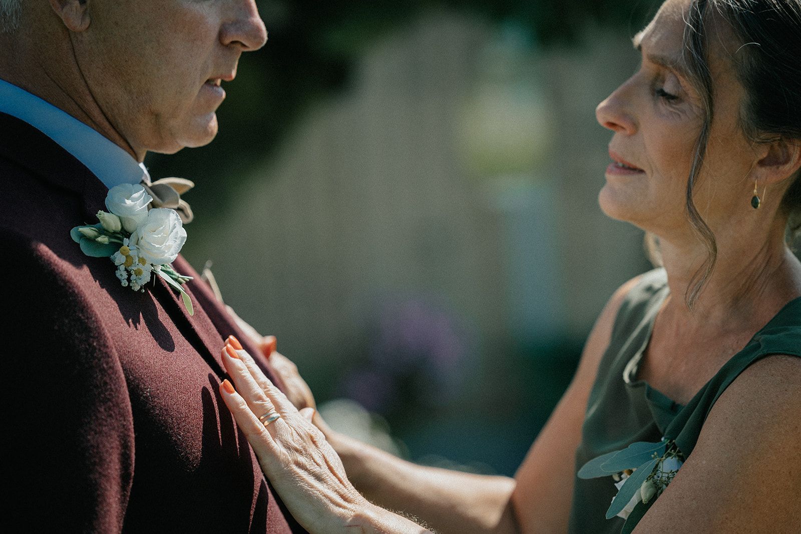 A woman is putting a flower on a man 's jacket.