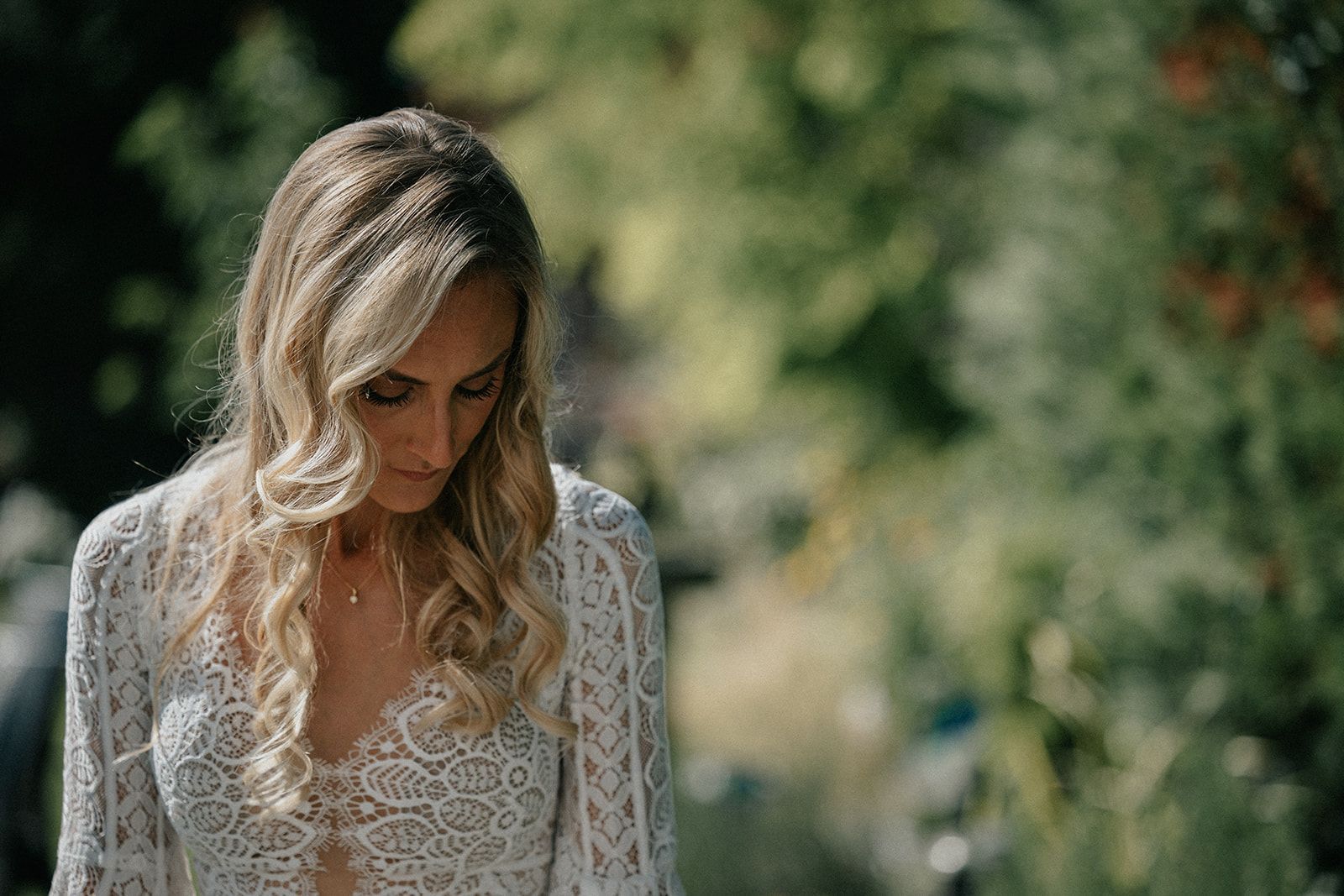 A woman in a white lace dress is looking down.