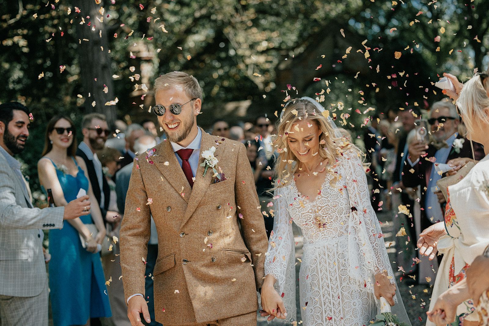 A bride and groom are walking down the aisle surrounded by confetti.