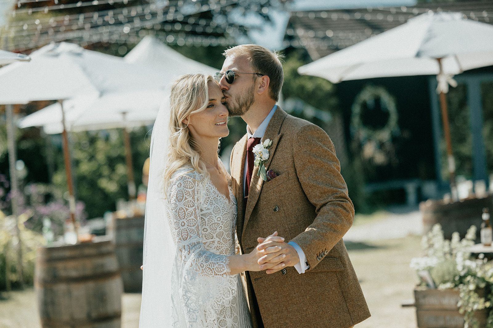 A bride and groom are kissing while holding hands at their wedding.