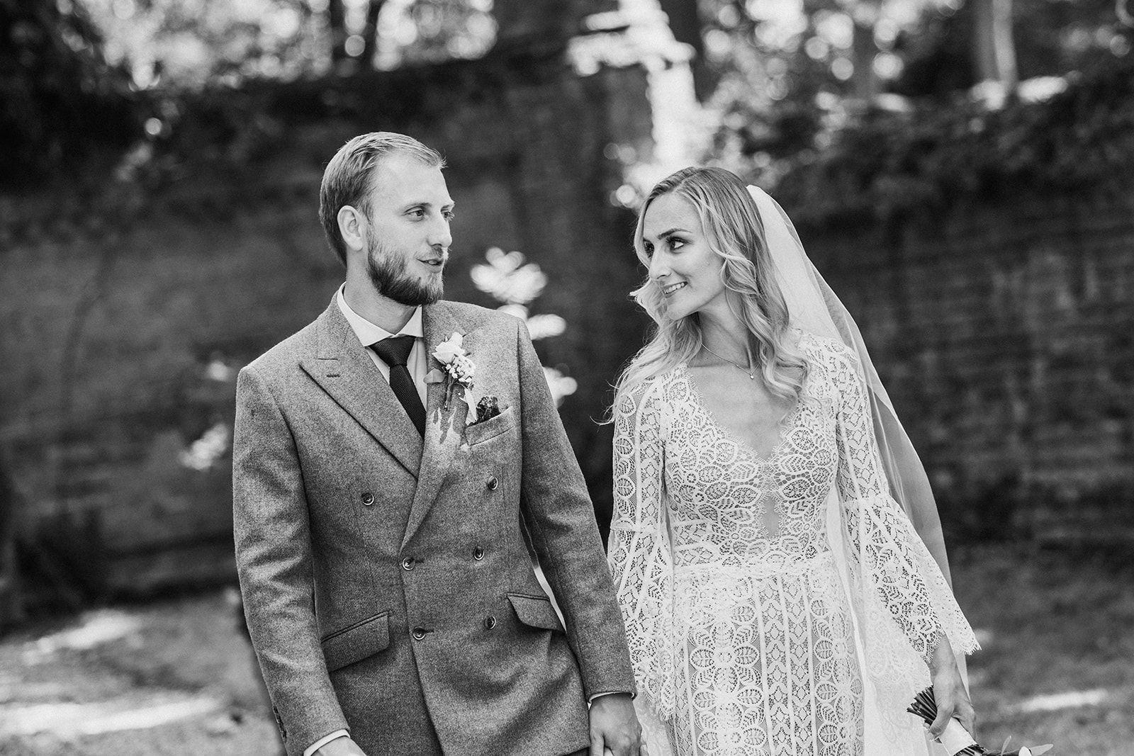 A black and white photo of a bride and groom holding hands.
