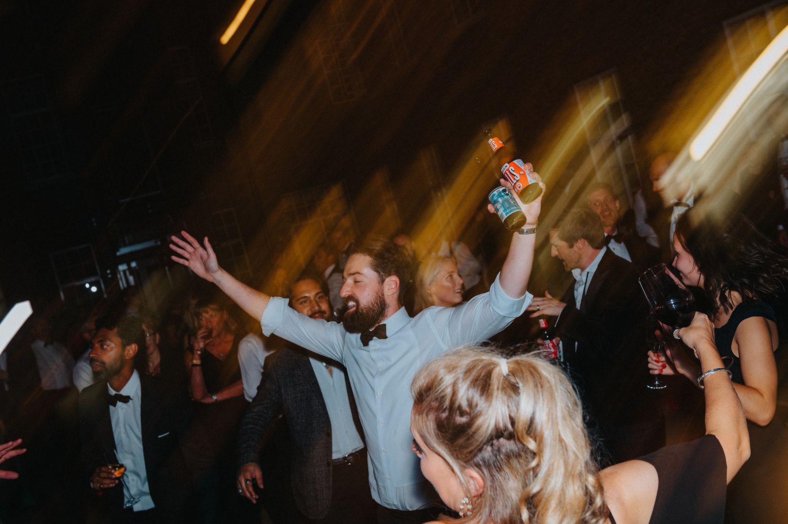A group of people are dancing at a party in a dark room.