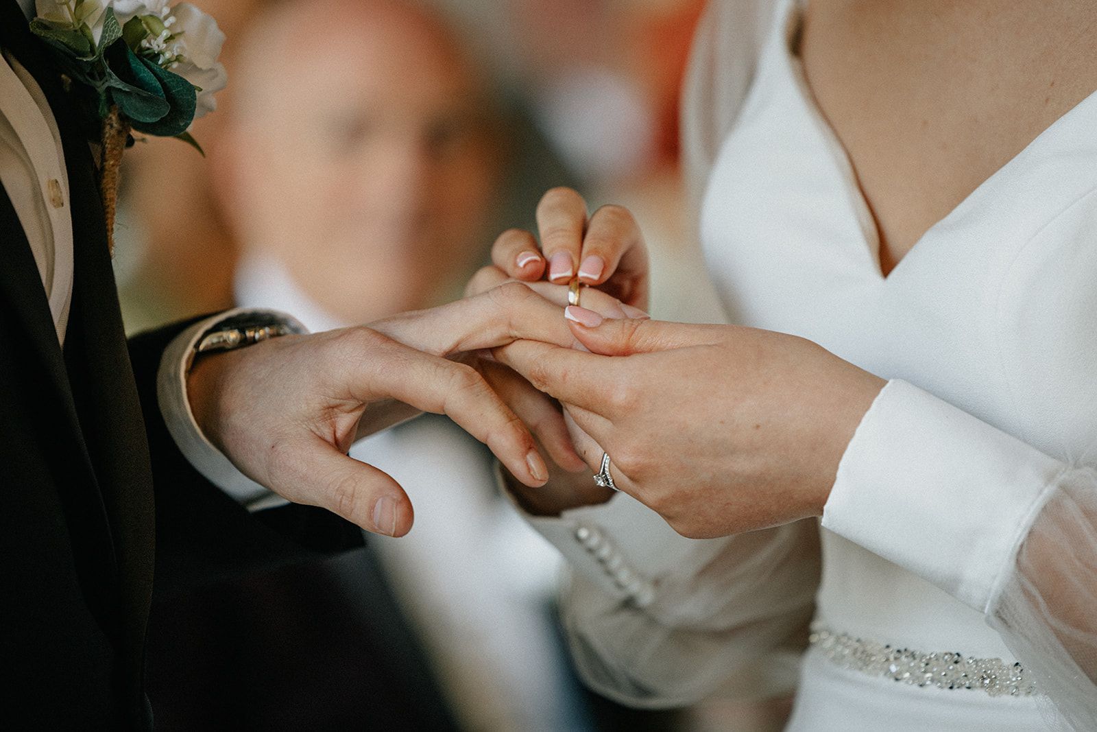 A bride is putting a wedding ring on the groom 's finger.