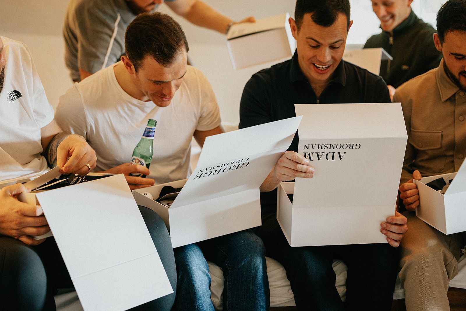 A group of men are sitting on a couch reading a book.