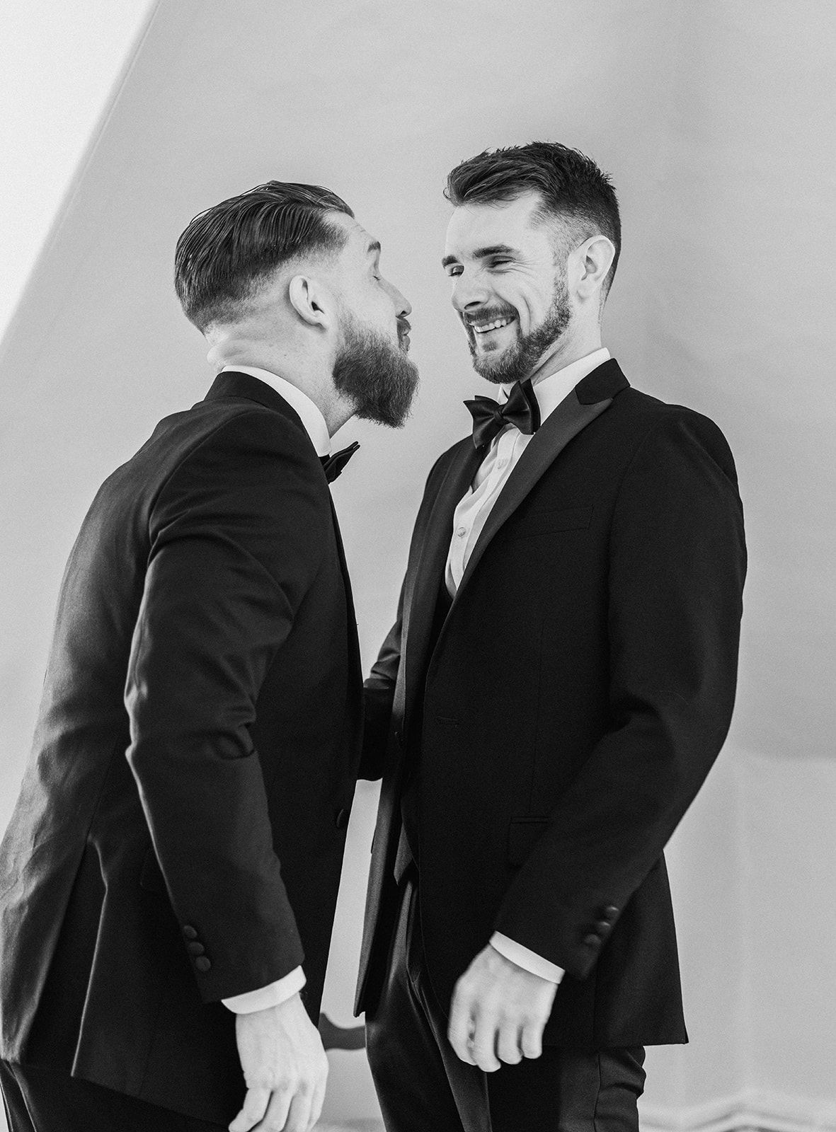 Two men in tuxedos are looking at each other in a black and white photo.