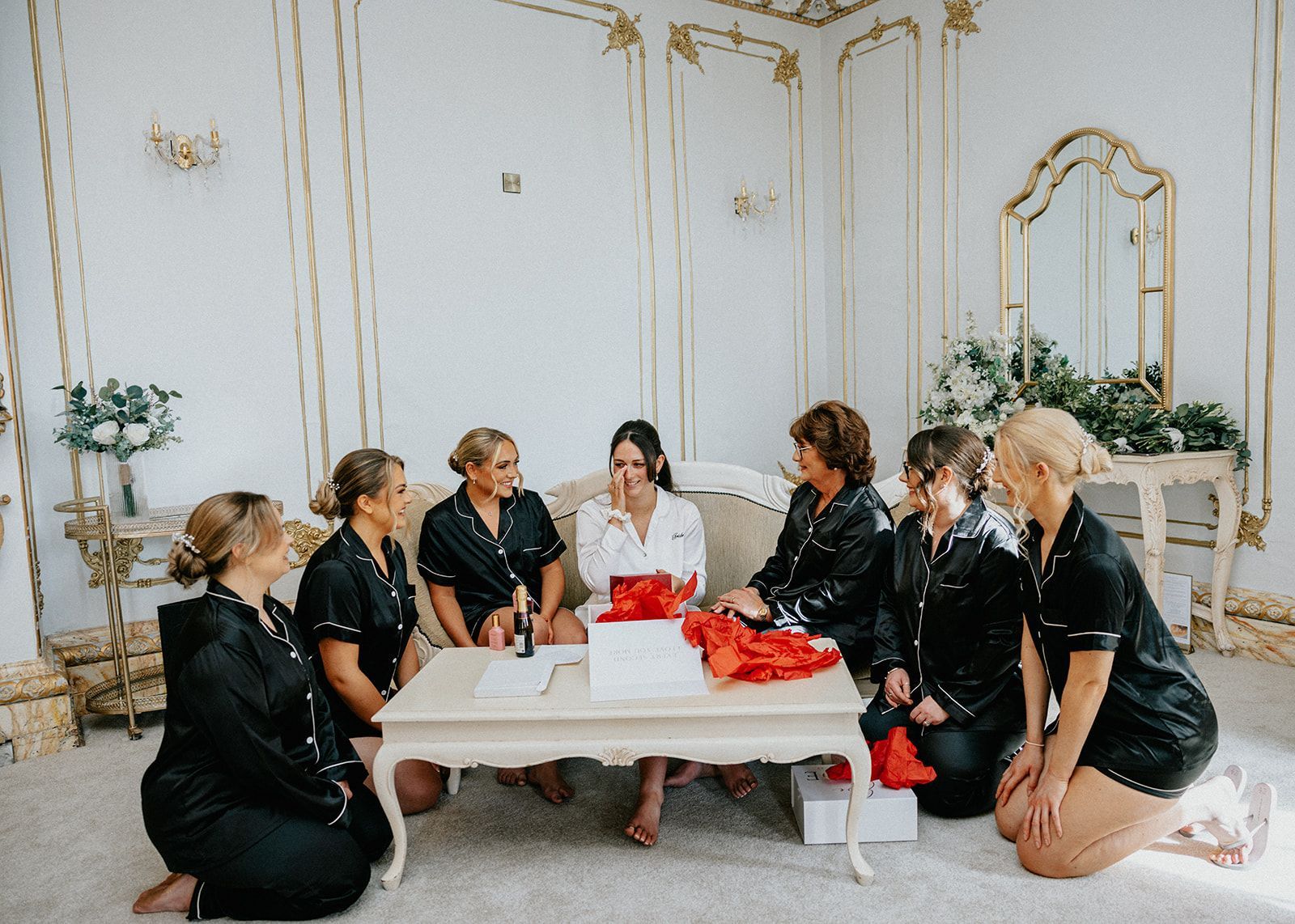 A bride and her bridesmaids are sitting around a table in a room.