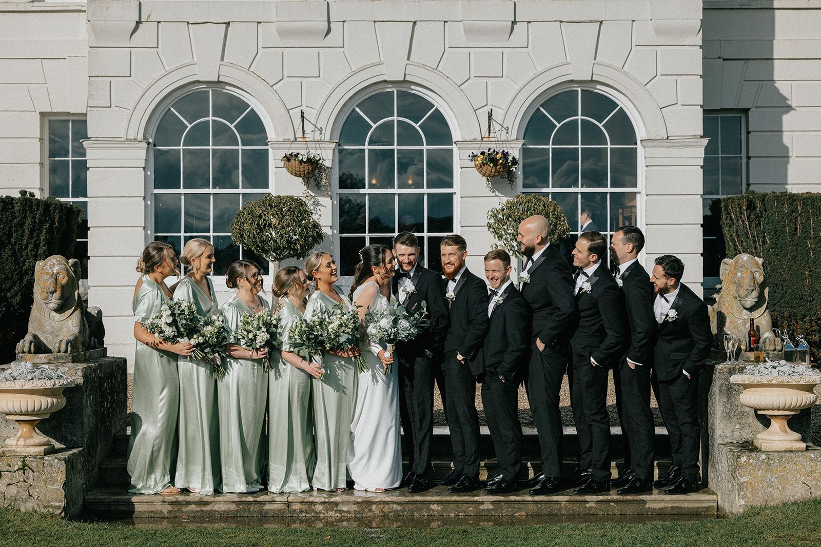A bride and groom are posing for a picture with their wedding party in front of a building.