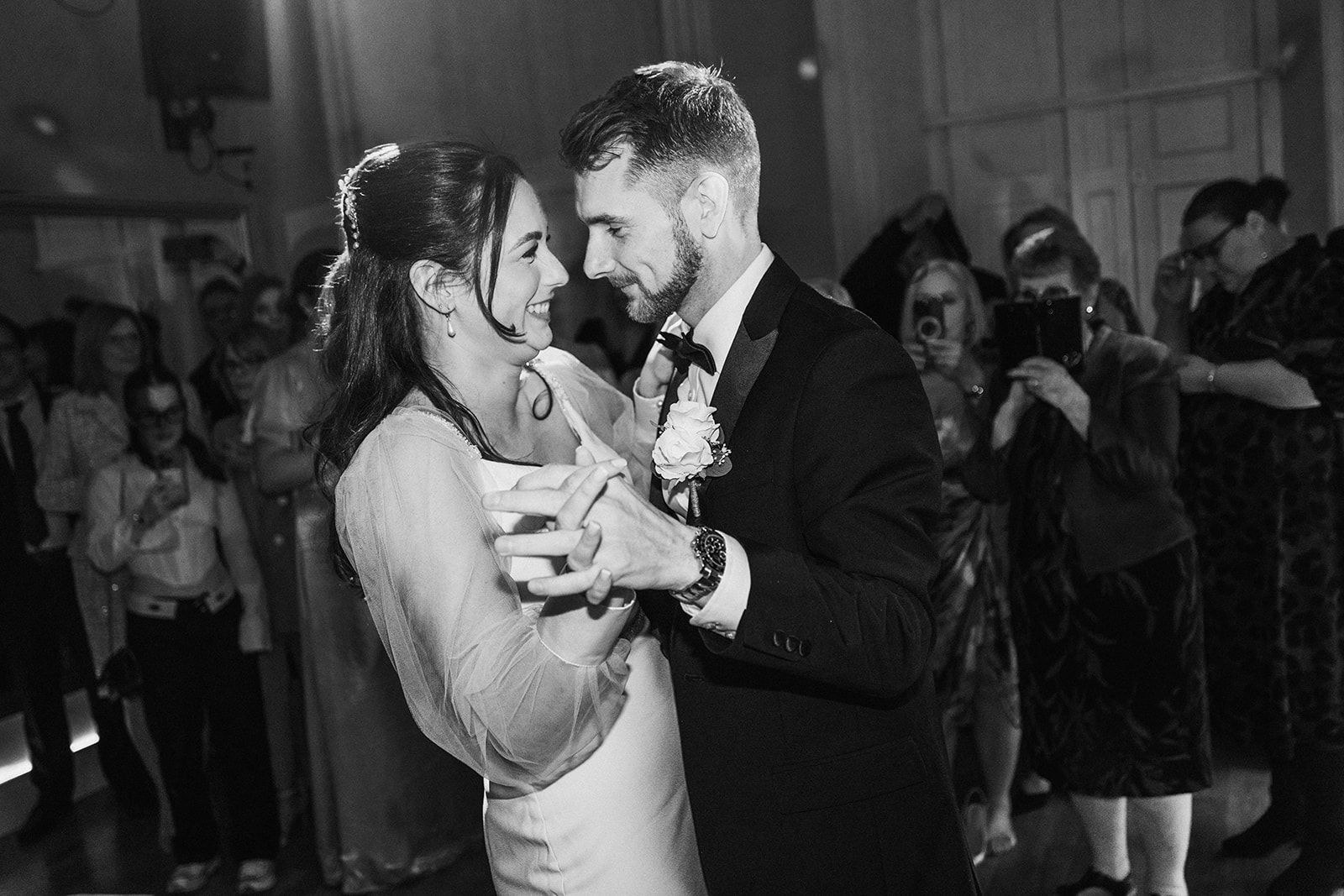 A black and white photo of a bride and groom dancing at their wedding reception.