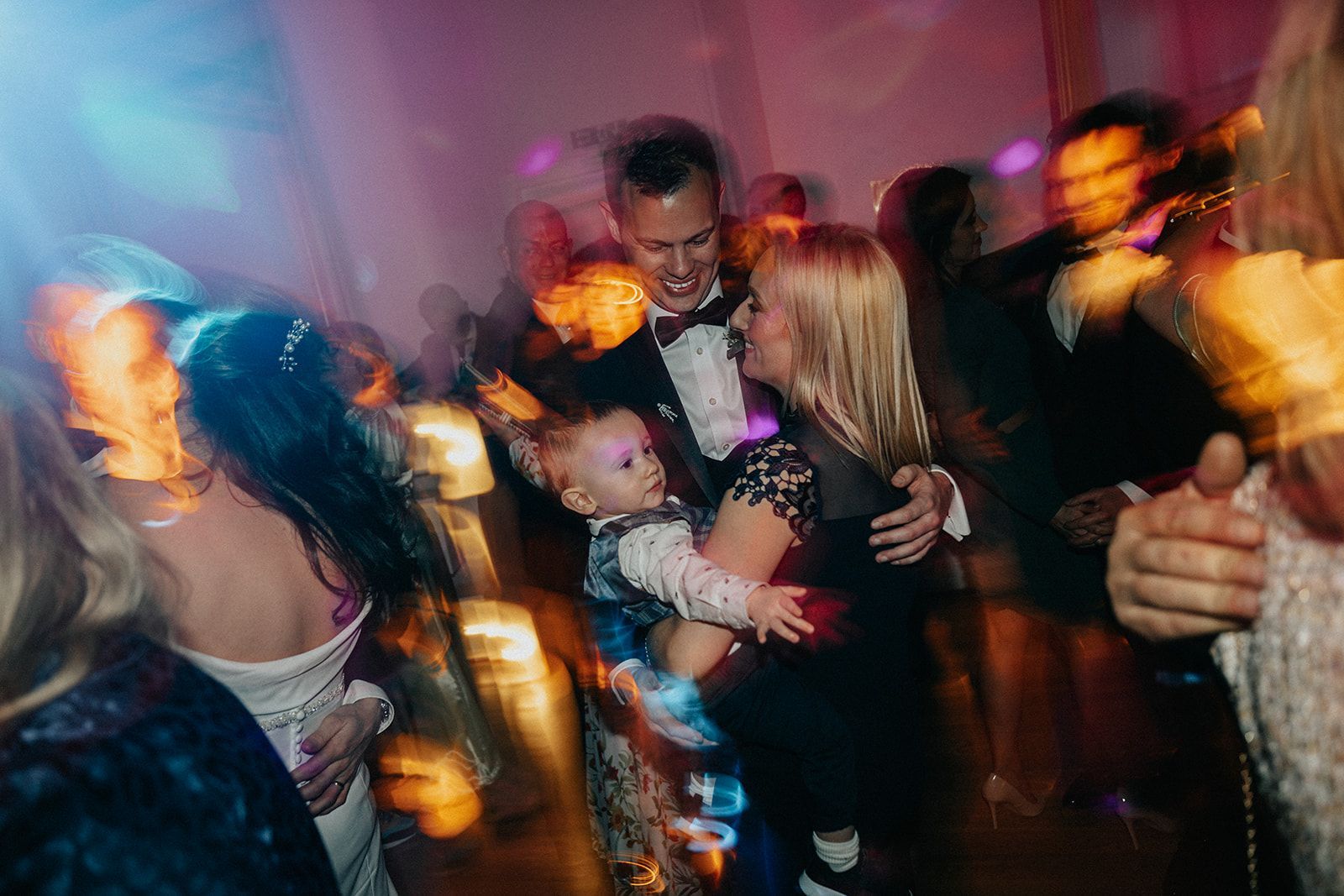 A woman is holding a baby in her arms while dancing at a party.