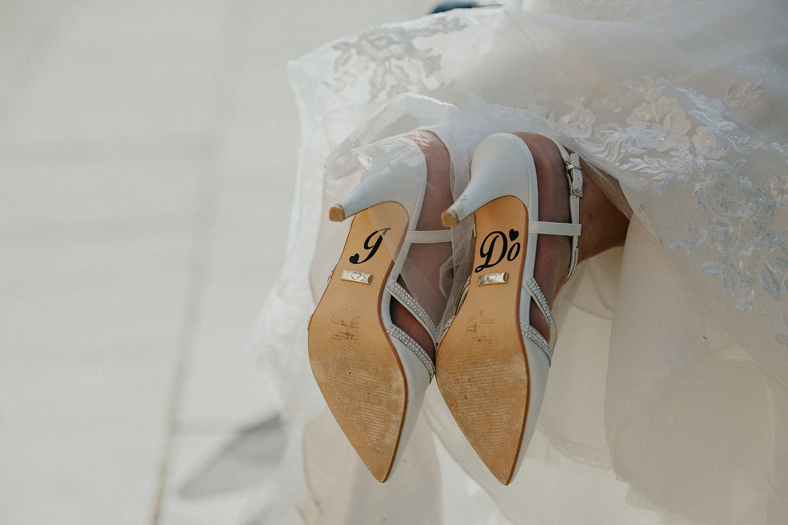 A pair of wedding shoes with the initials of the bride and groom on them.