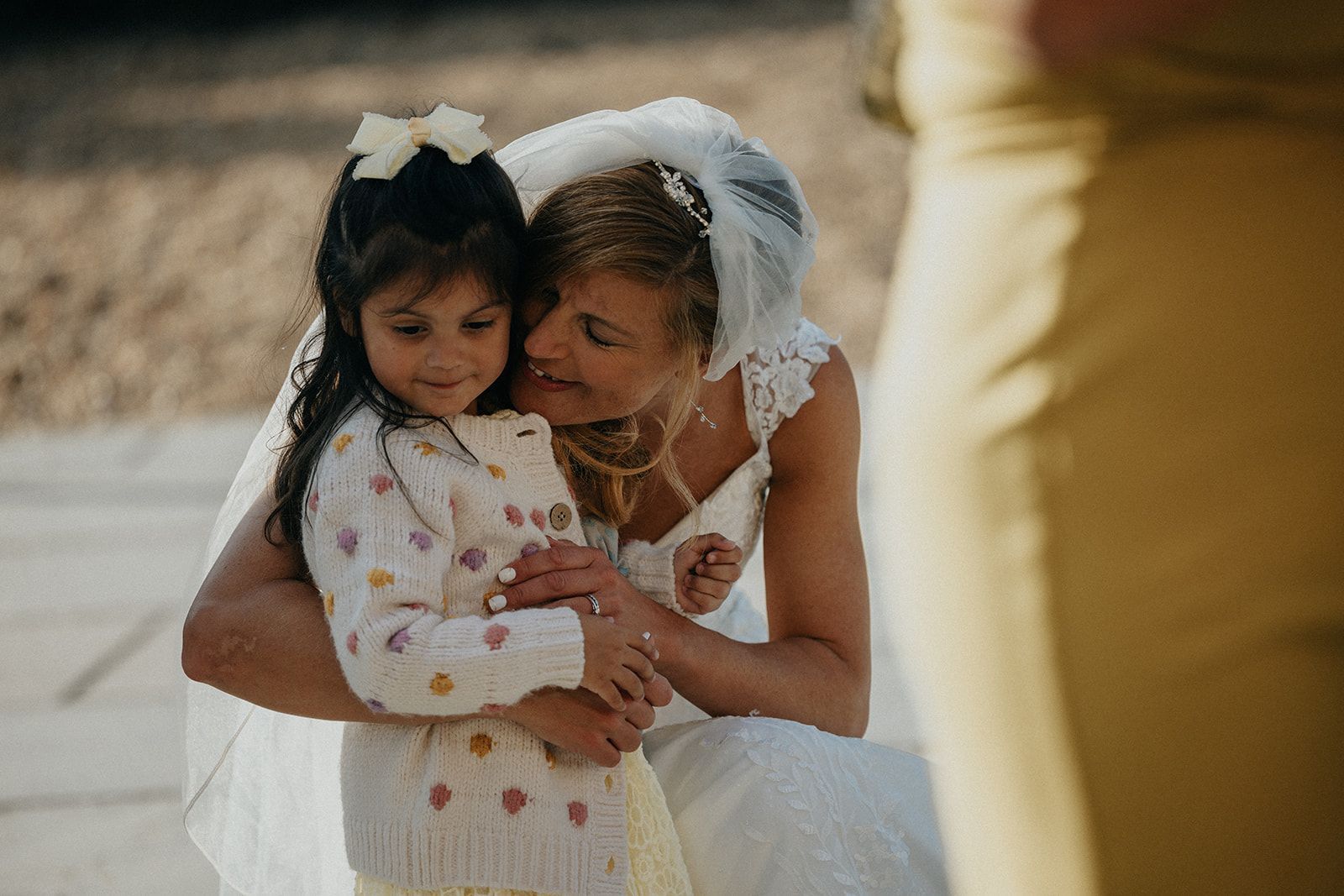 A bride is hugging a little girl at her wedding.
