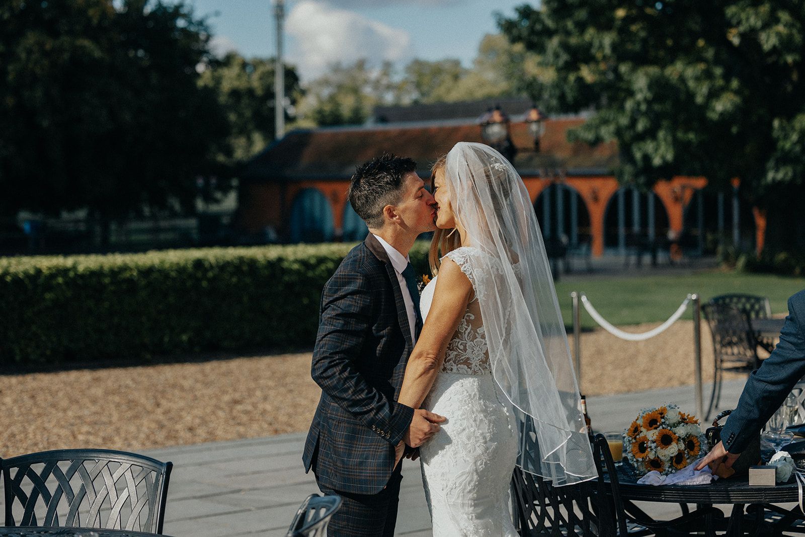 A bride and groom are kissing in front of a building.