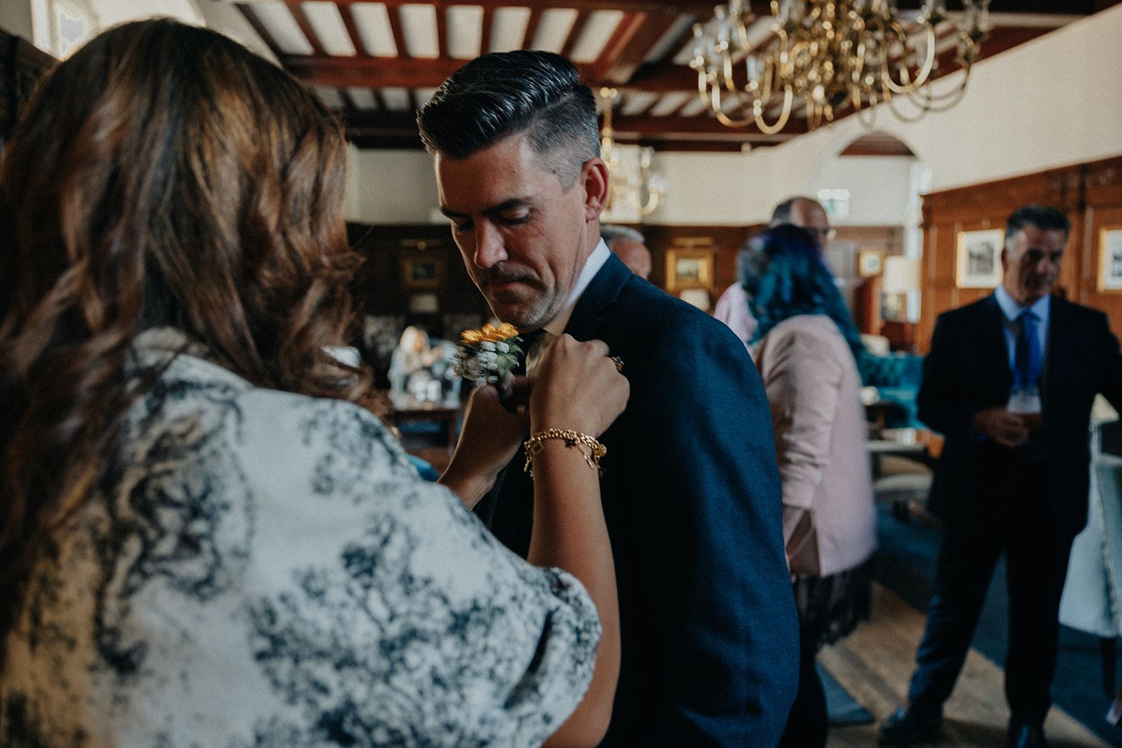 A woman is helping a man with his tie at a wedding reception.