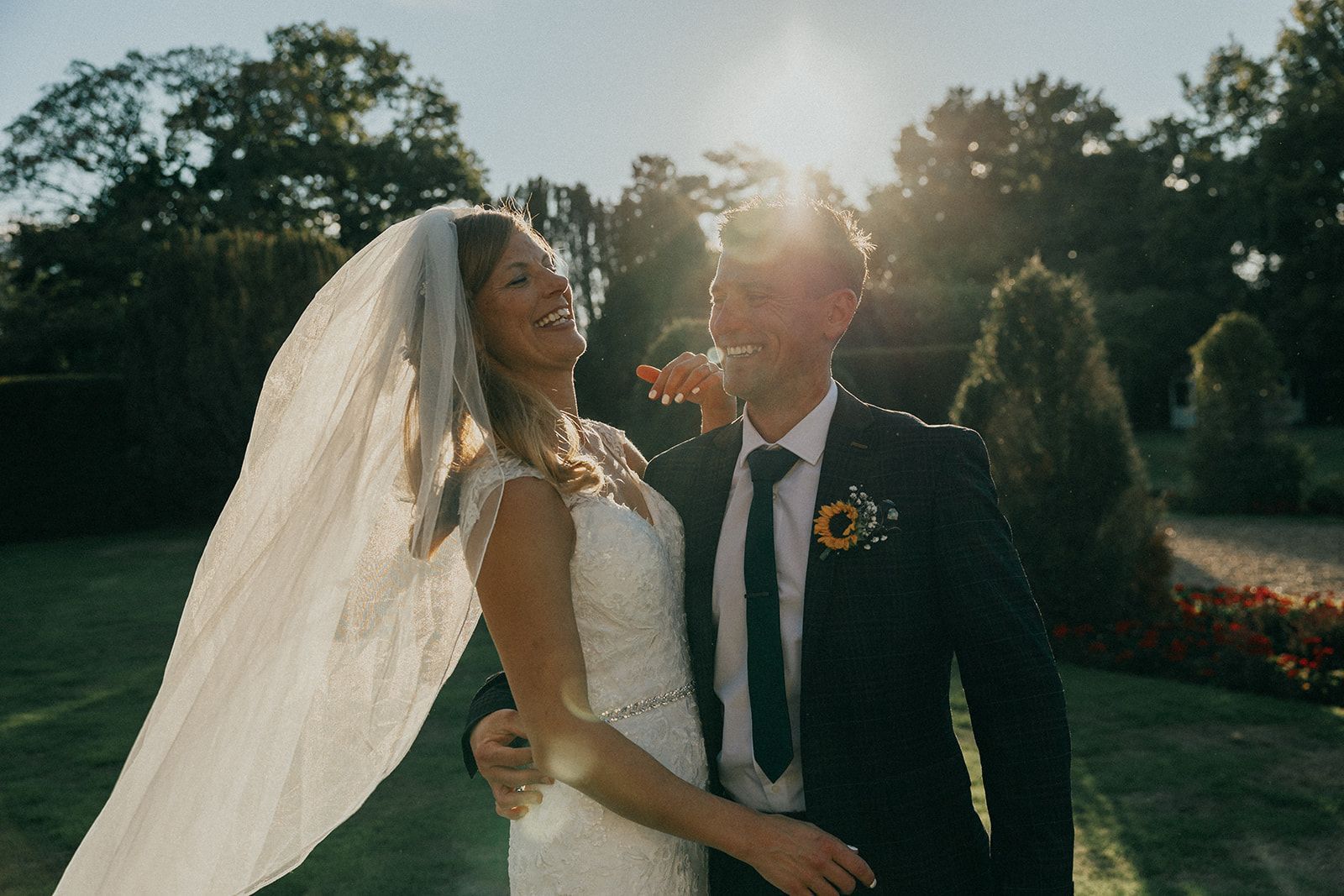 A bride and groom are standing next to each other in a park.