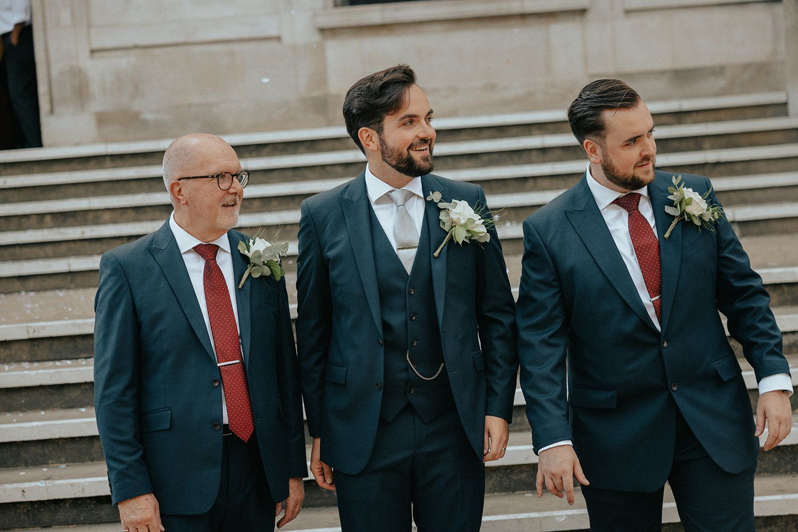 Three men in suits and ties are standing on a set of stairs.