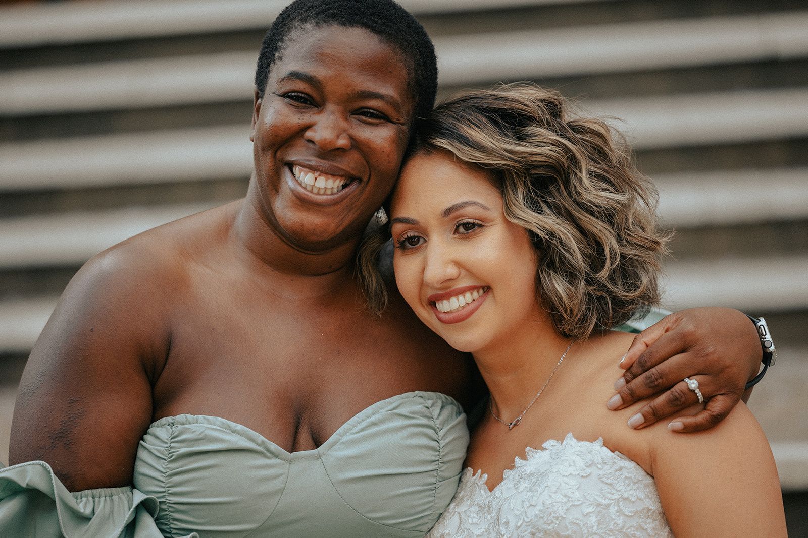 A bride and her bridesmaid are posing for a picture together.