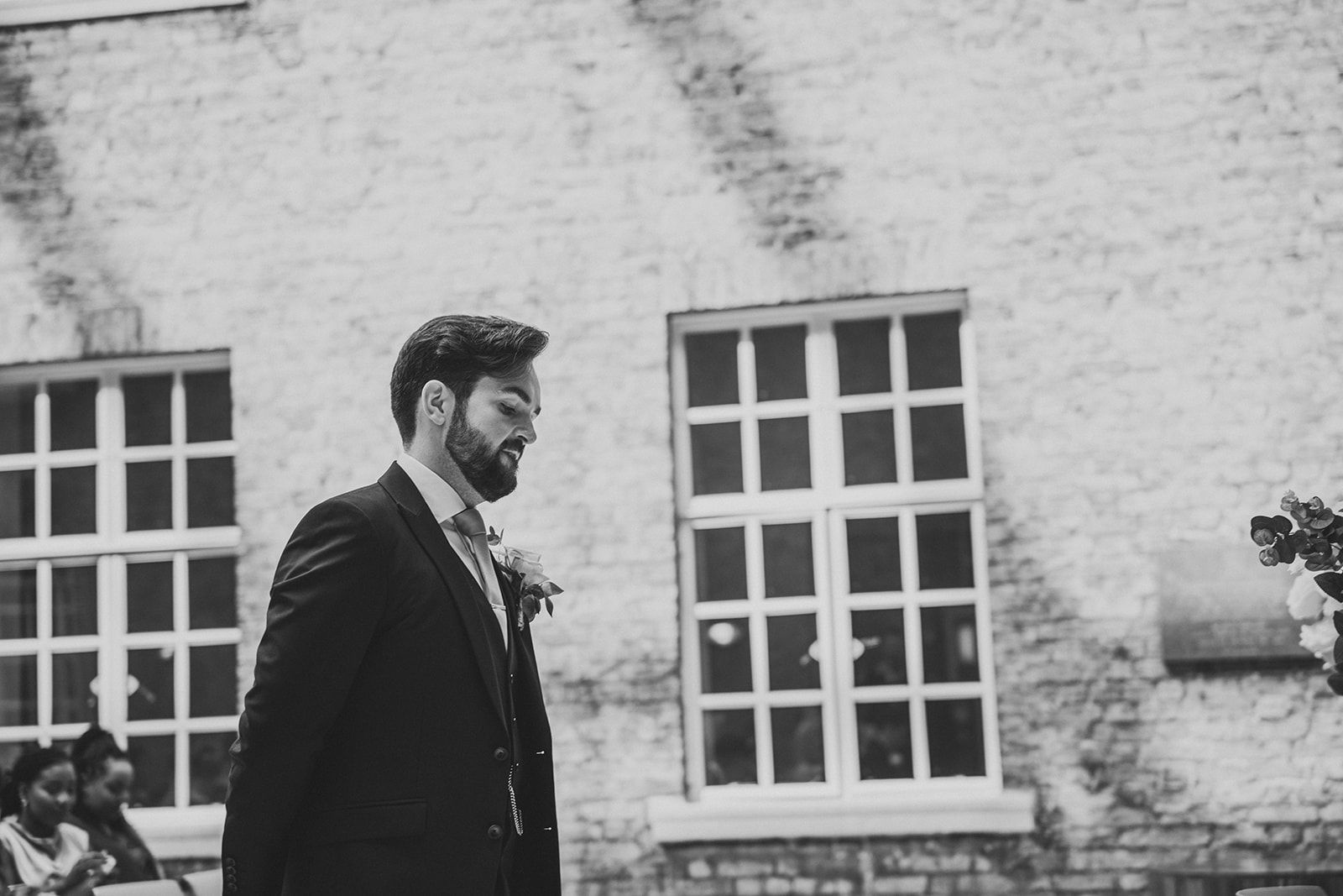 A man in a suit and tie is walking down the aisle at a wedding.