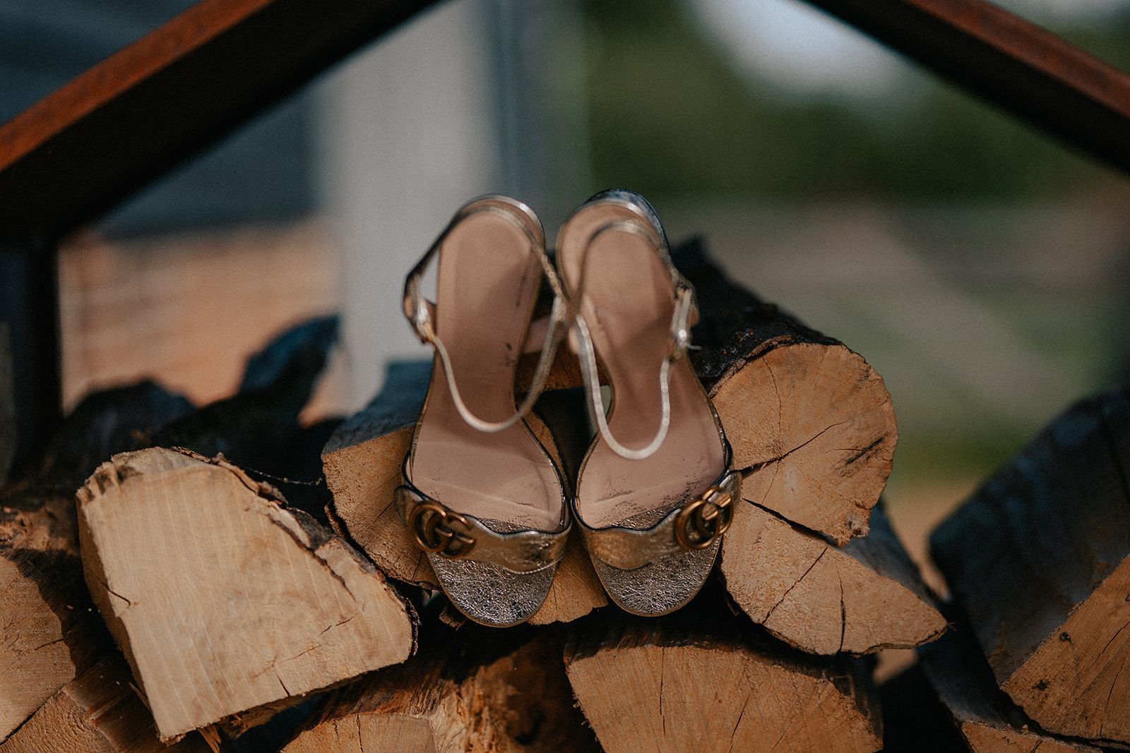 A pair of wedding shoes sitting on top of a pile of logs.