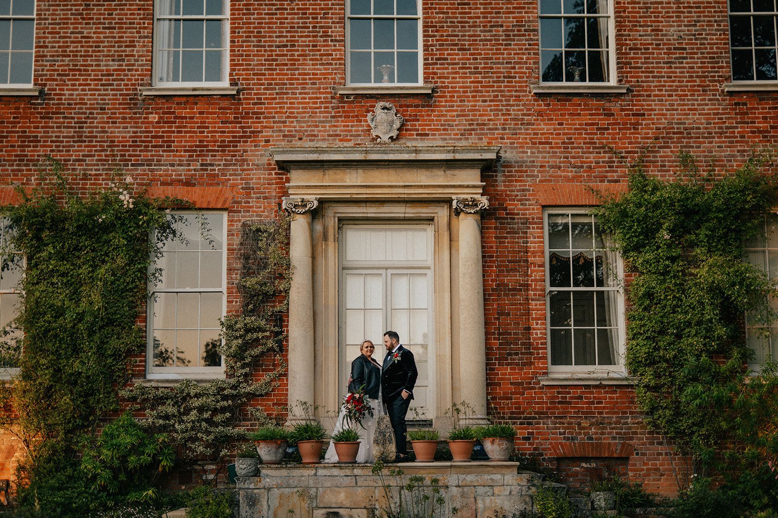 Two men are standing in front of a large brick building.