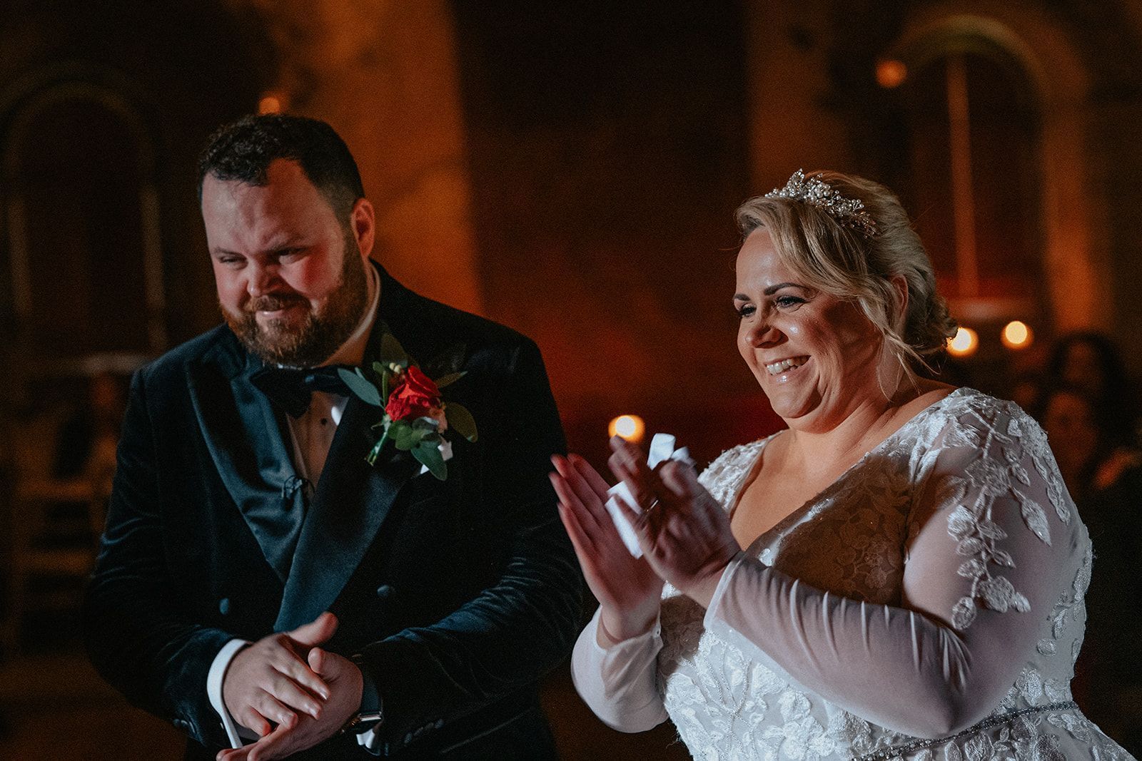 A bride and groom are clapping at their wedding reception.