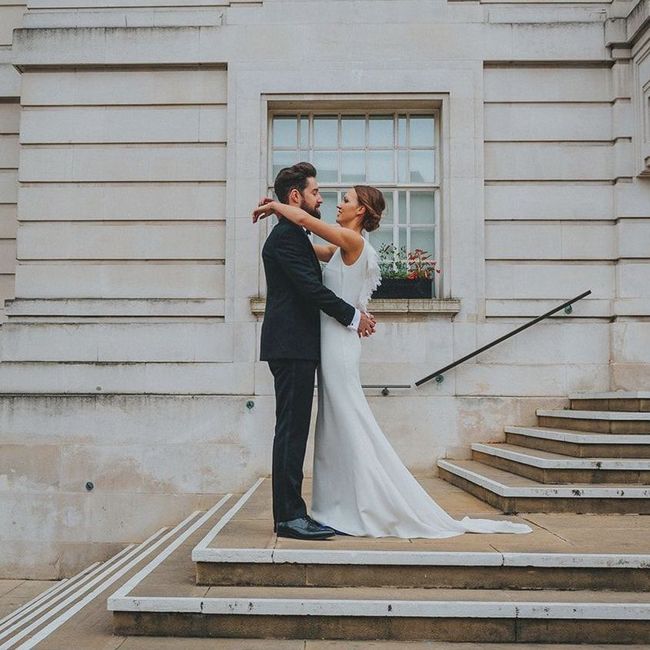 A bride and groom are kissing on the steps of a building.