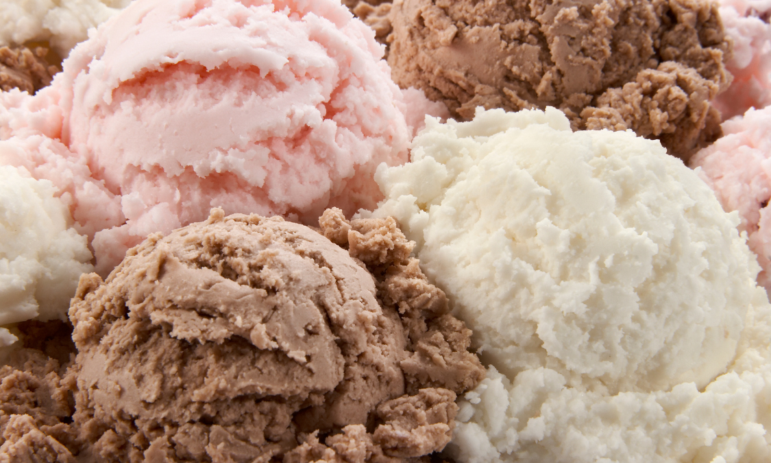 Red, white, and blue layered cake decorated with American flags, on a blue cake stand, and table setting.