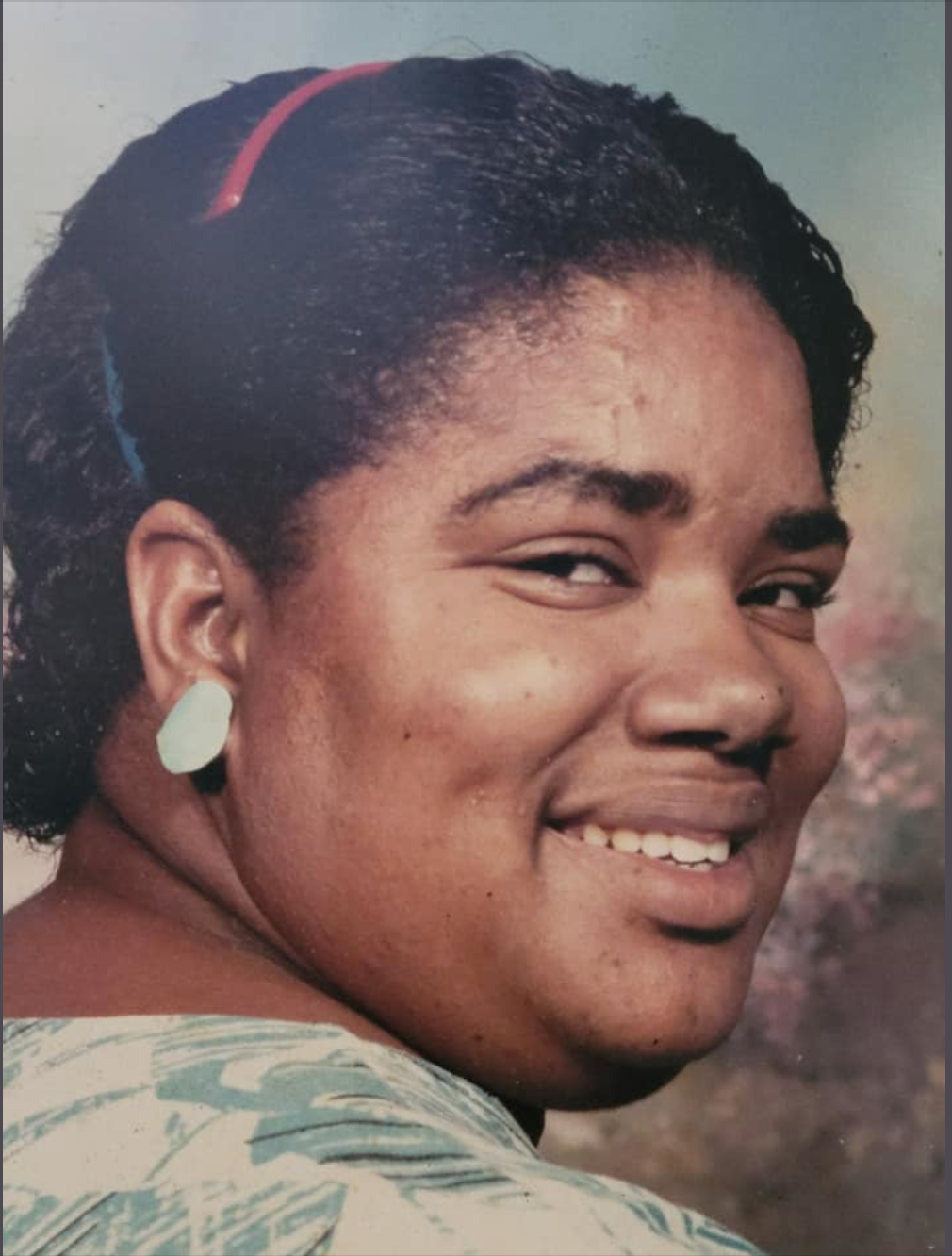 A woman wearing white earrings is smiling for the camera