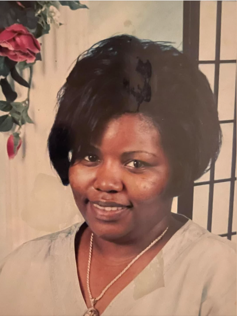A woman wearing a necklace and a white shirt smiles for the camera