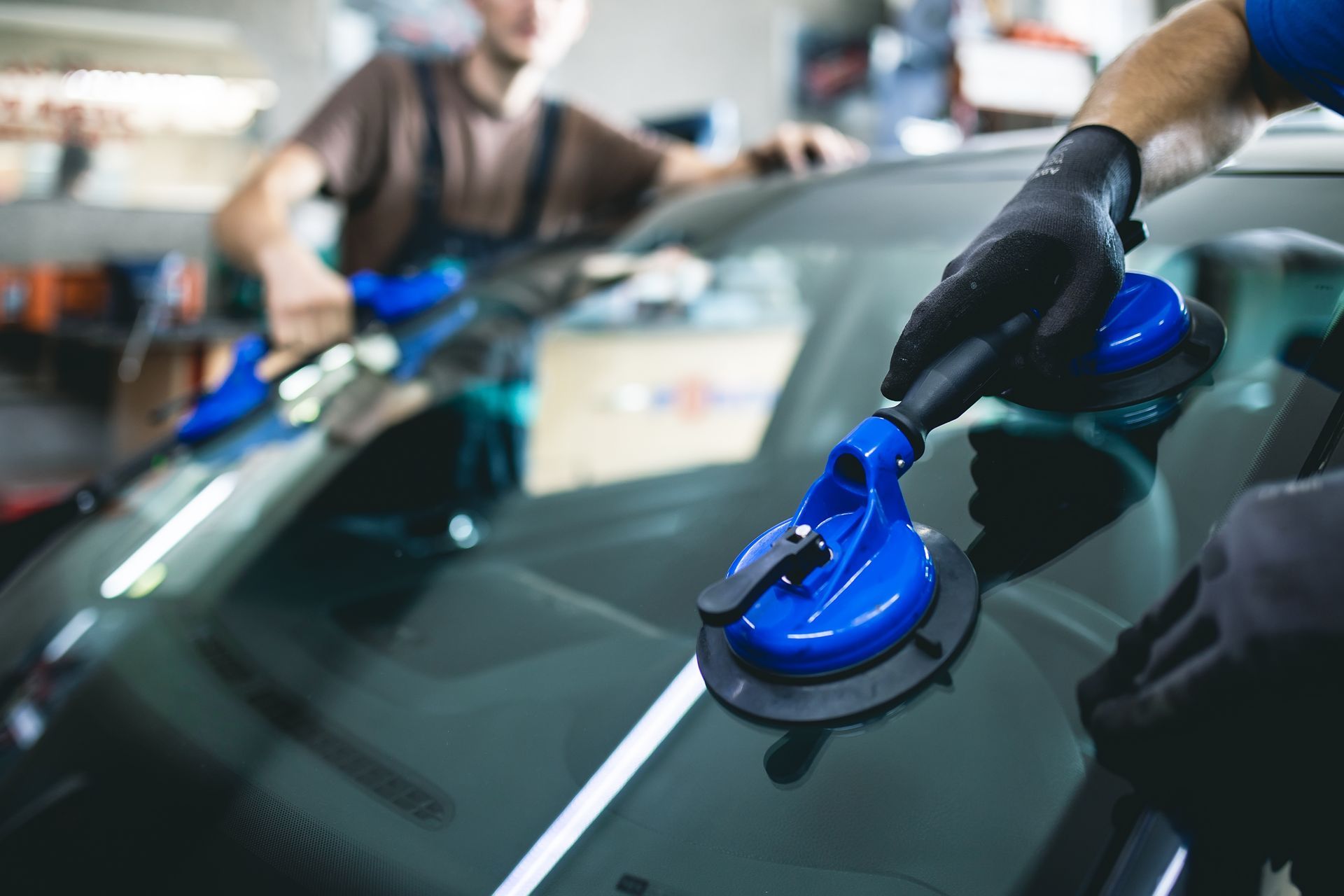Two auto glass technicians are installing a windshield on a car