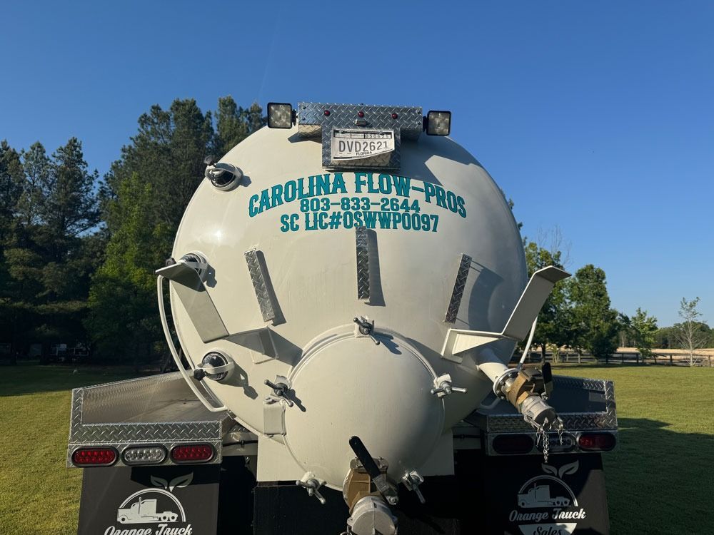 Rear view of a Carolina Flow-Pros truck tank; gray, on a sunny day, with green grass in the background.