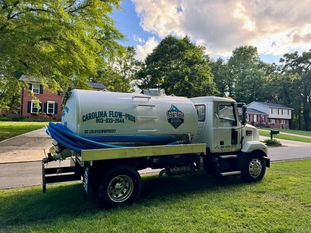 Septic truck parked on a grassy lawn, with a tank that reads 