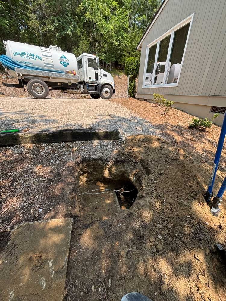 Truck near a house and a hole dug in the ground.