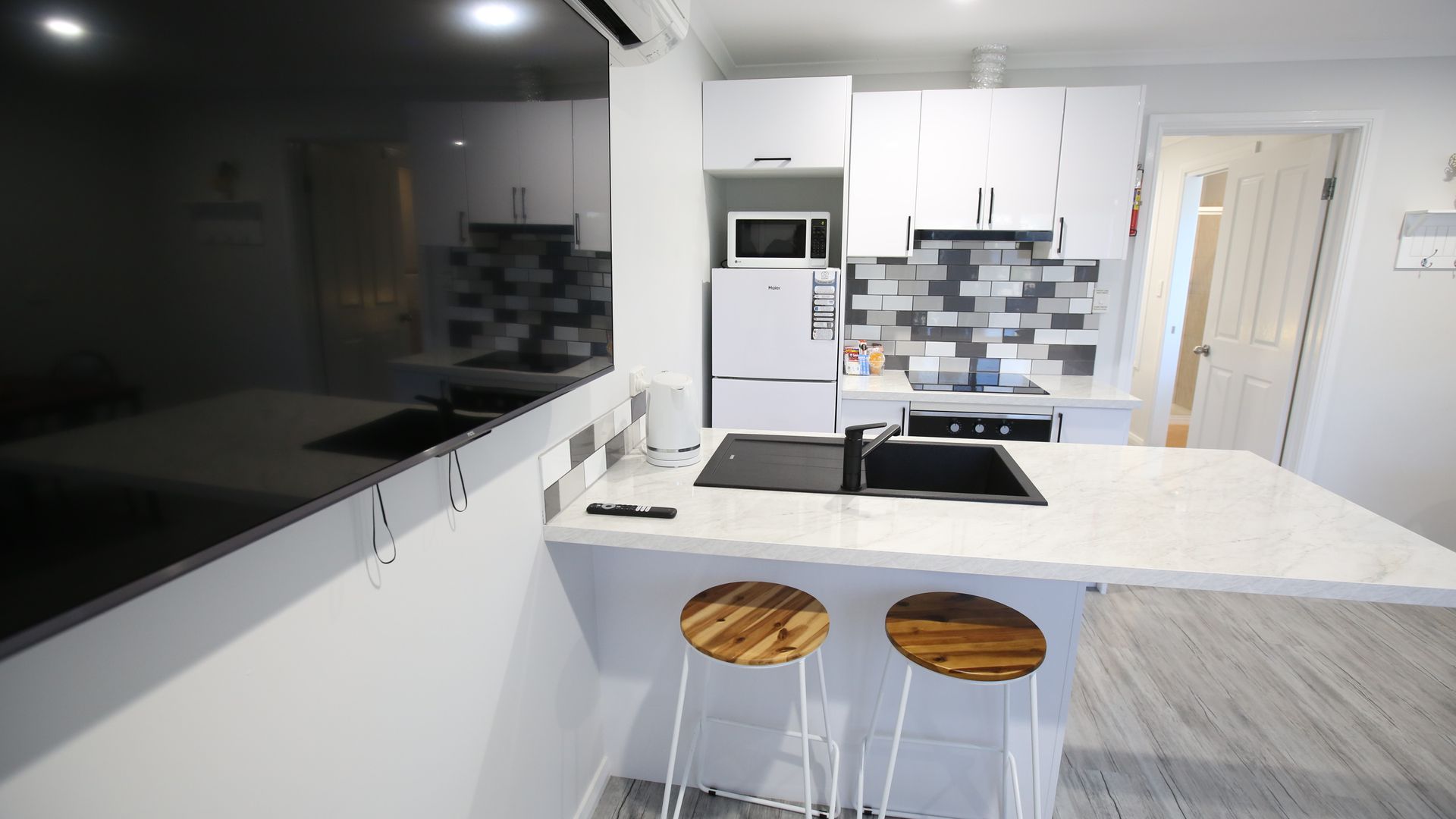 A kitchen with white cabinets , a sink , and stools.