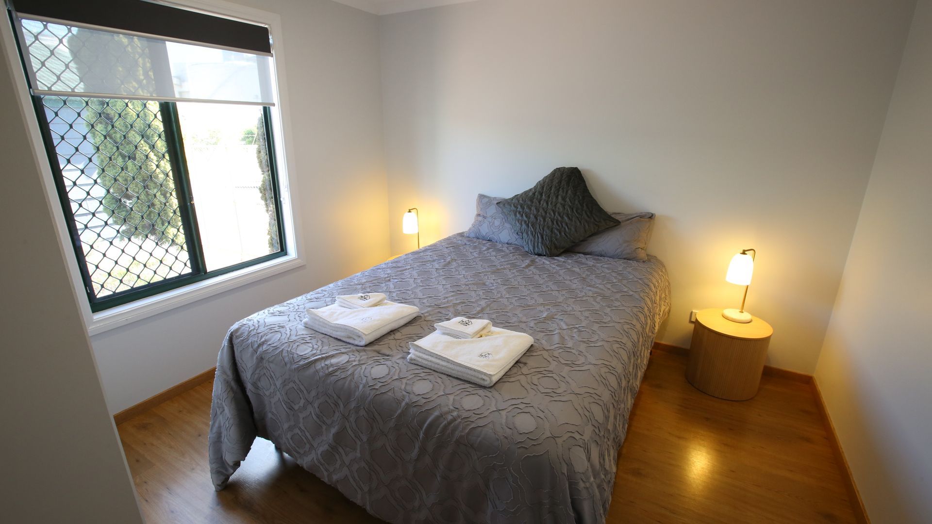 A bedroom with a bed , two lamps and a window.