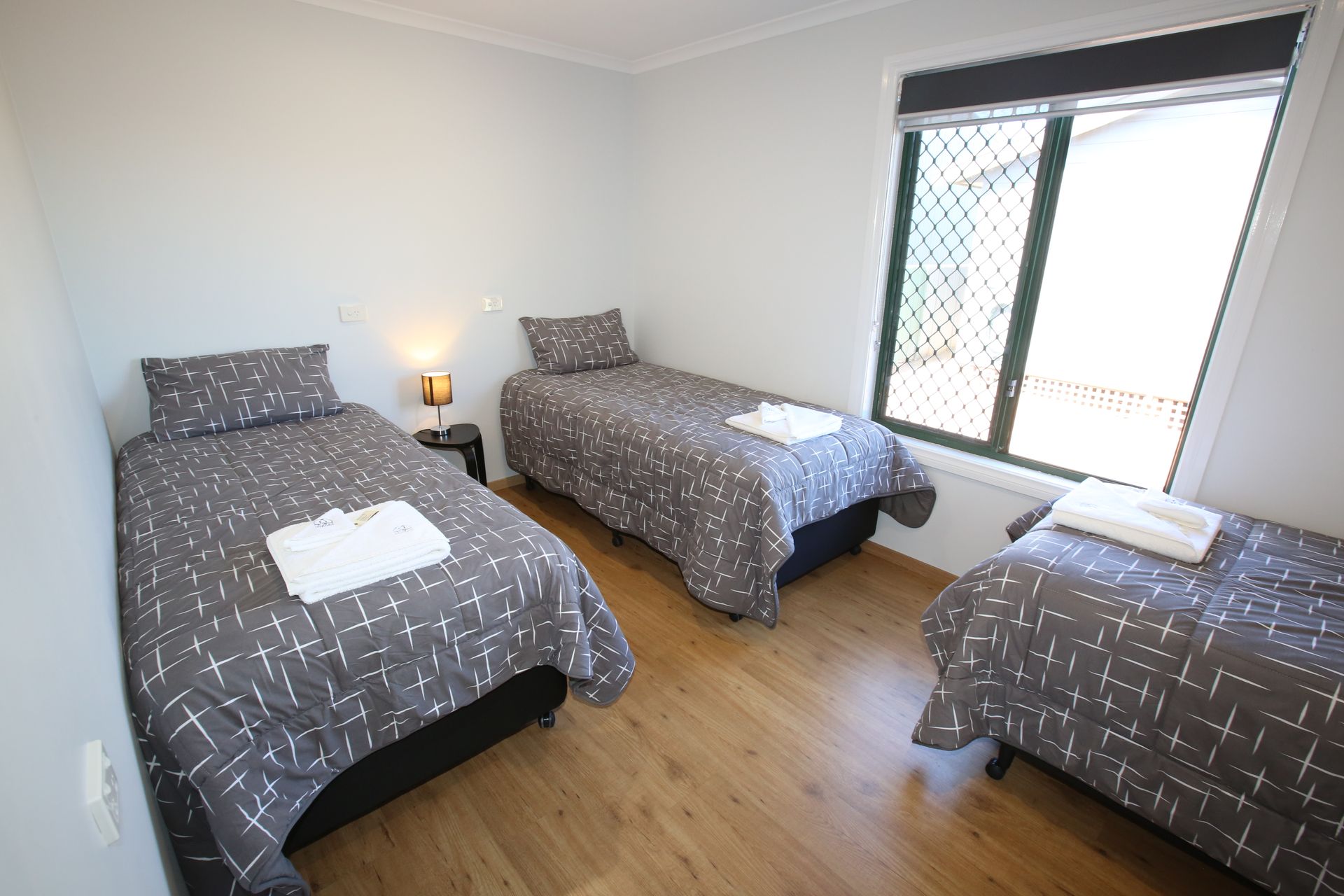 A bedroom with three beds and a window.
