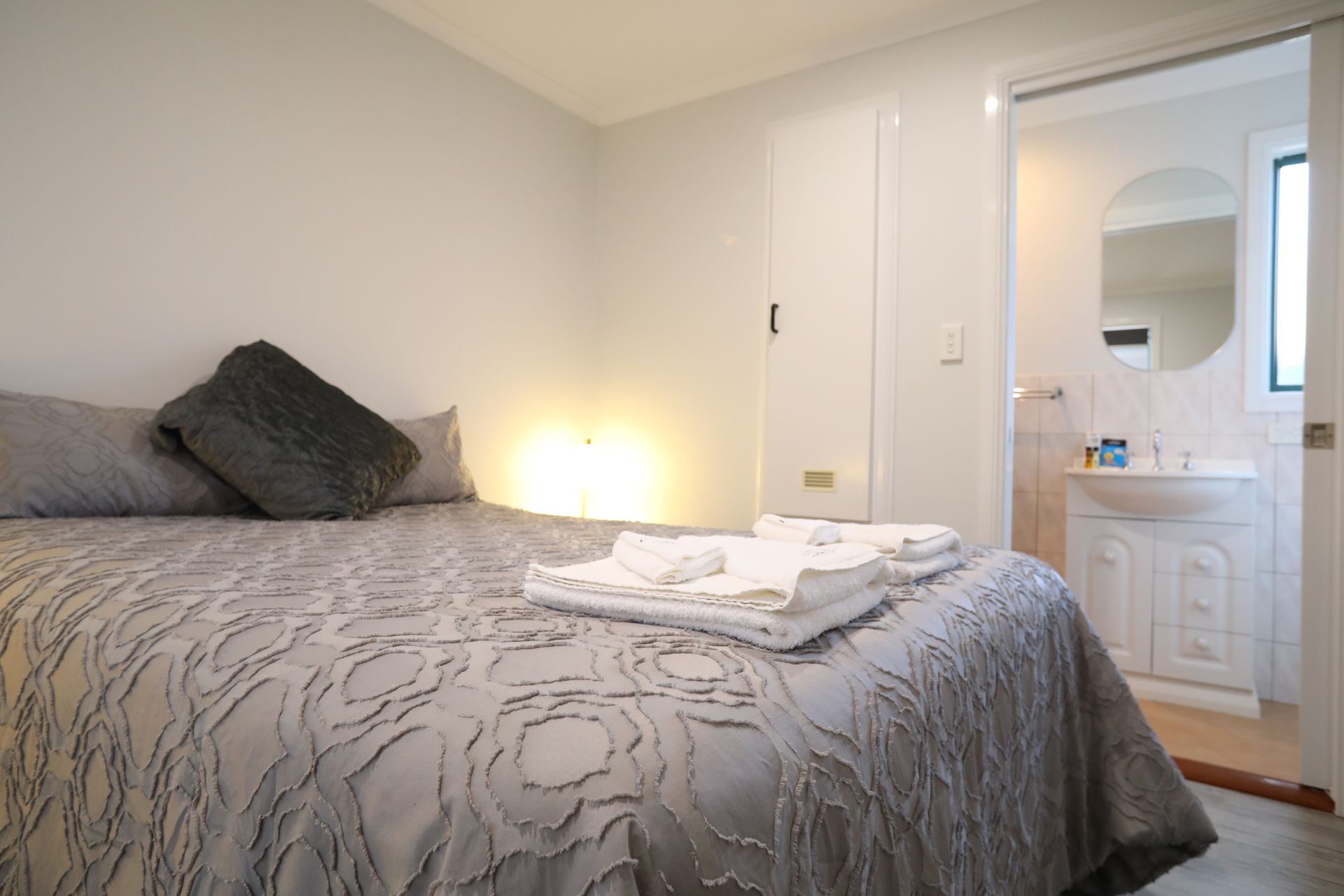 A bedroom with a bed and a bathroom in the background.