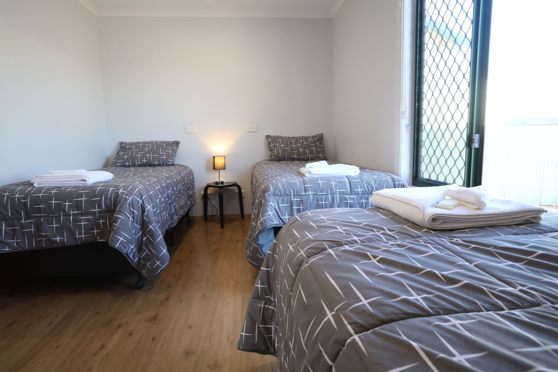 A bedroom with three beds and a window.