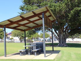 A picnic table under a covered shelter in a park.