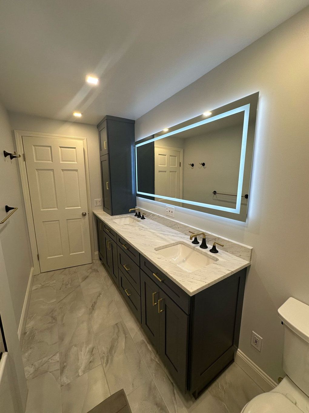 A bathroom with two sinks , a toilet , and a large mirror.