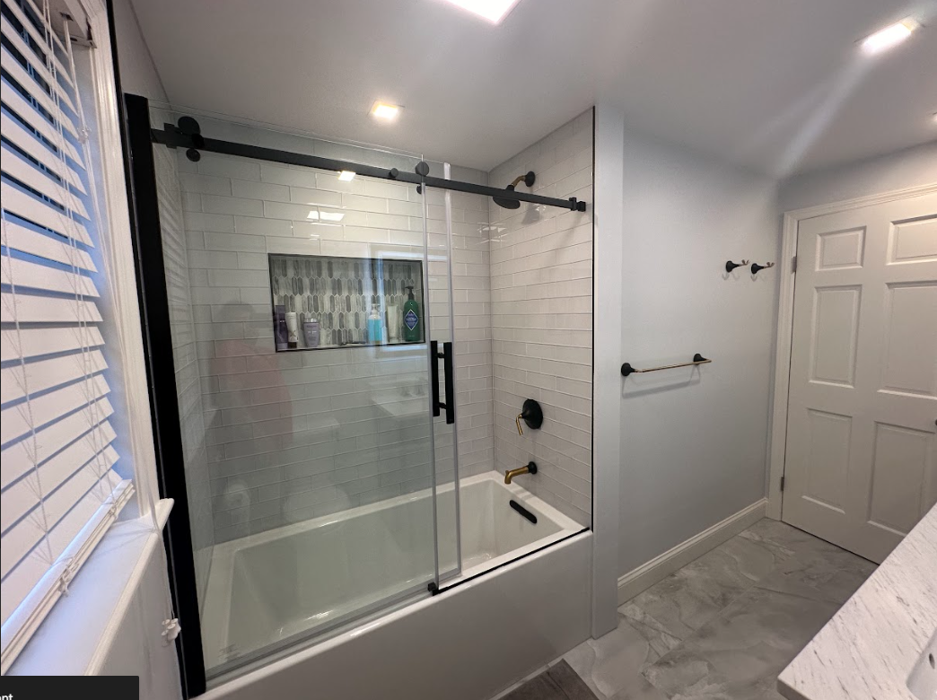 A bathroom with a bathtub and a sliding glass shower door.