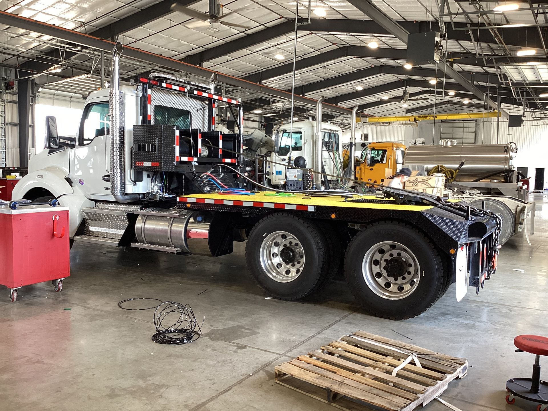 Woman in straw hat smiles, holding wine glass near a lake.